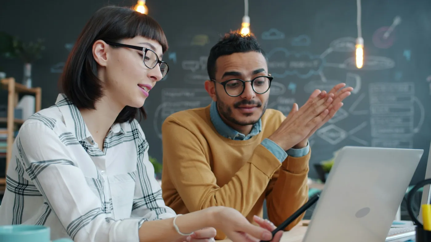 Two coworkers collaborating at a laptop in a modern office